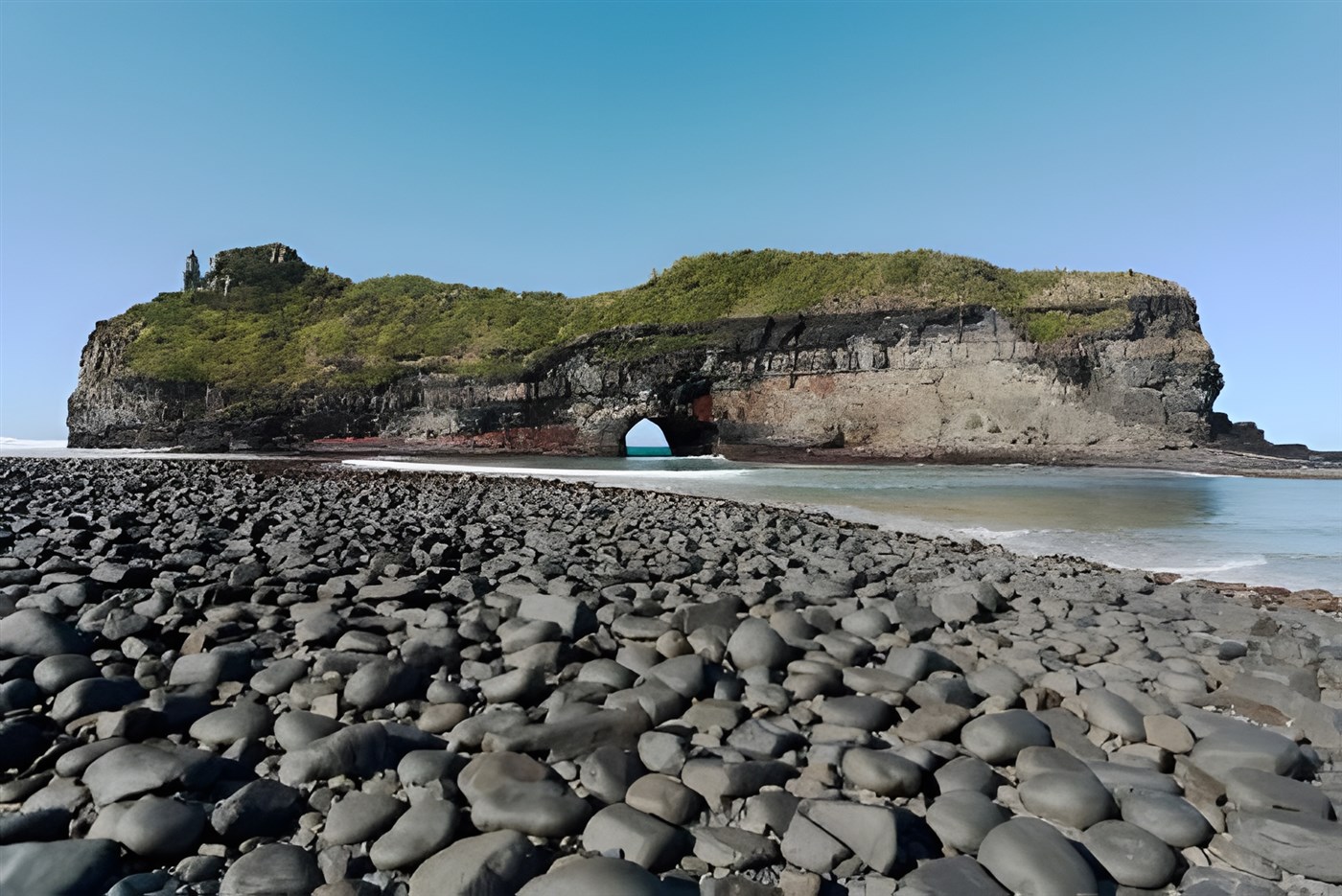 The iconic Hole in The Wall, a stunning natural rock formation on the Wild Coast of the Eastern Cape, South Africa, with the ocean visible through the hole.