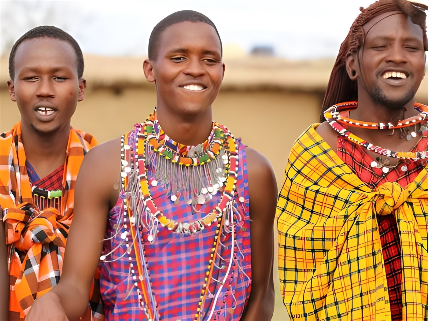 Masaai villagers in Kenya wearing colourful clothing and beads on the occasion of tourists visiting their homes. This image is being used to illustrate a section of a blog article discussing how responsible travel can protect lands, animals and communities.