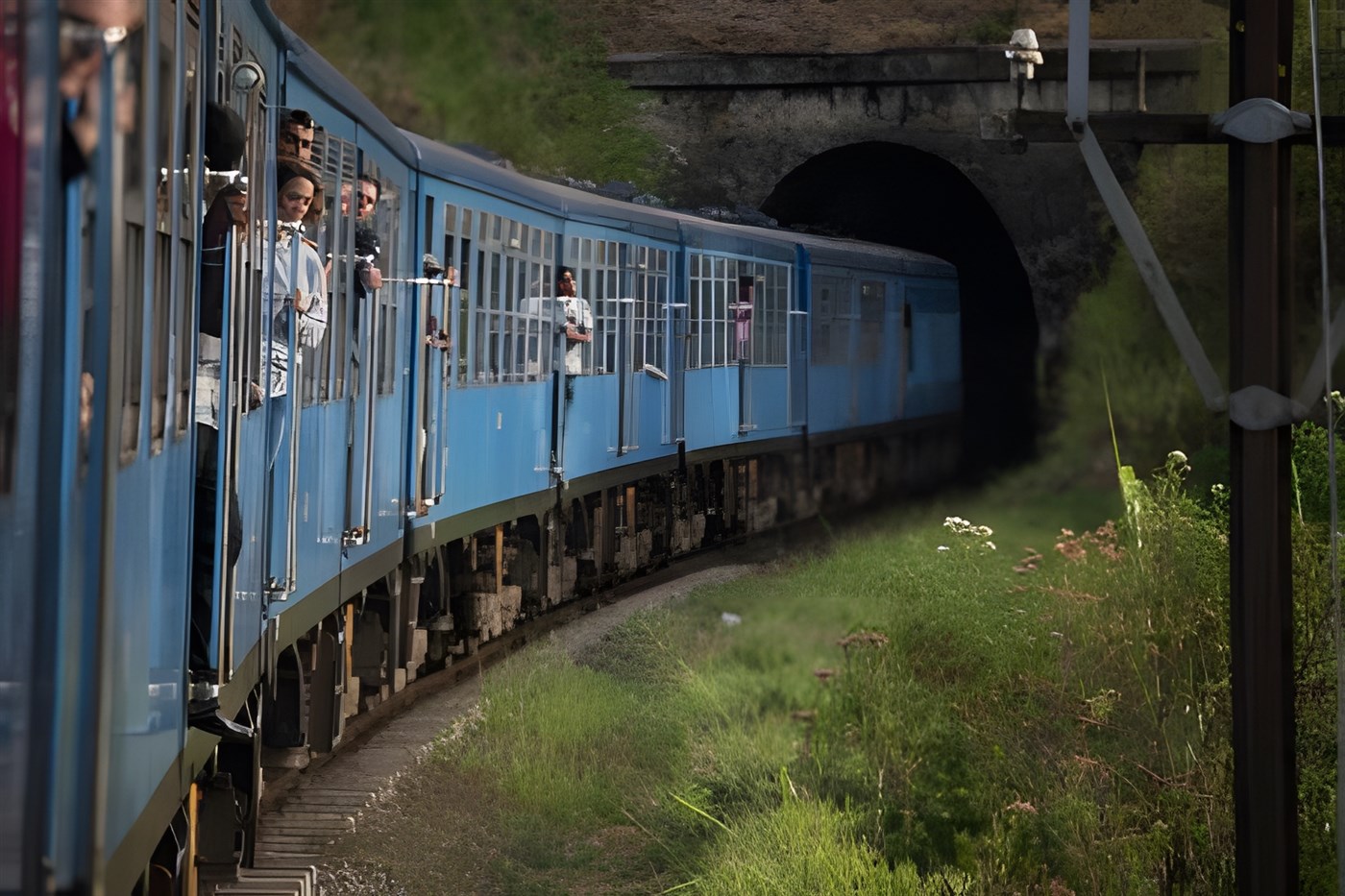 One of the more modern chinese-built blue trains in Sri Lanka photographed with a passanger leaning out.
